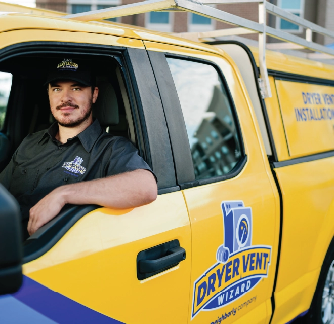 Two male Dryer Vent Wizard professionals sit in company truck smiling.