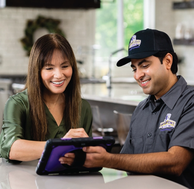 Homeowner and Dryer Vent Wizard pro sit in kitchen and review a company ipad together.