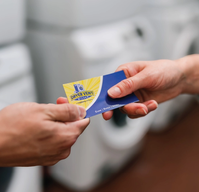 Up close view of two hands holding a Dryer Vent Wizard business card.