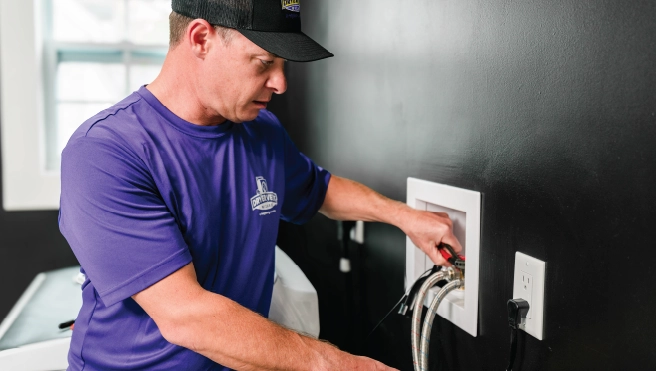 A dryer cleaning pro installs a new washing machine hose in a home.