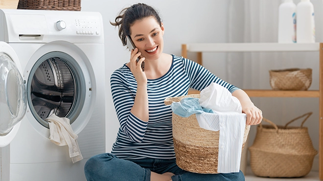Woman doing laundry and talking on cellphone.