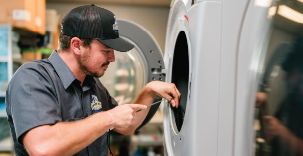 Professional dryer vent cleaning employee adjusting commercial dryer.