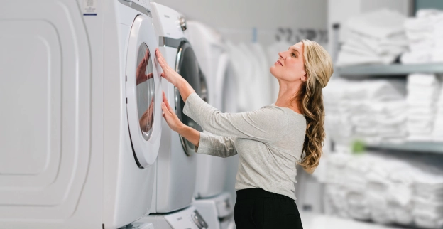 Woman closing door to a front facing commercial dryer in a stack of others.