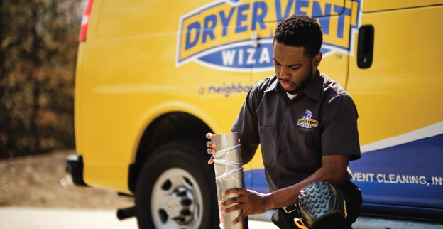 Male Dryer Vent Wizard professional cleaning duct line outside of company van.