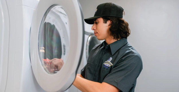 Uniformed dryer vent professional performing commercial dryer vent inspection.