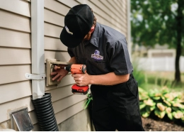 Dryer vent cleaning professional replacing exterior dryer vent cover with power tool.