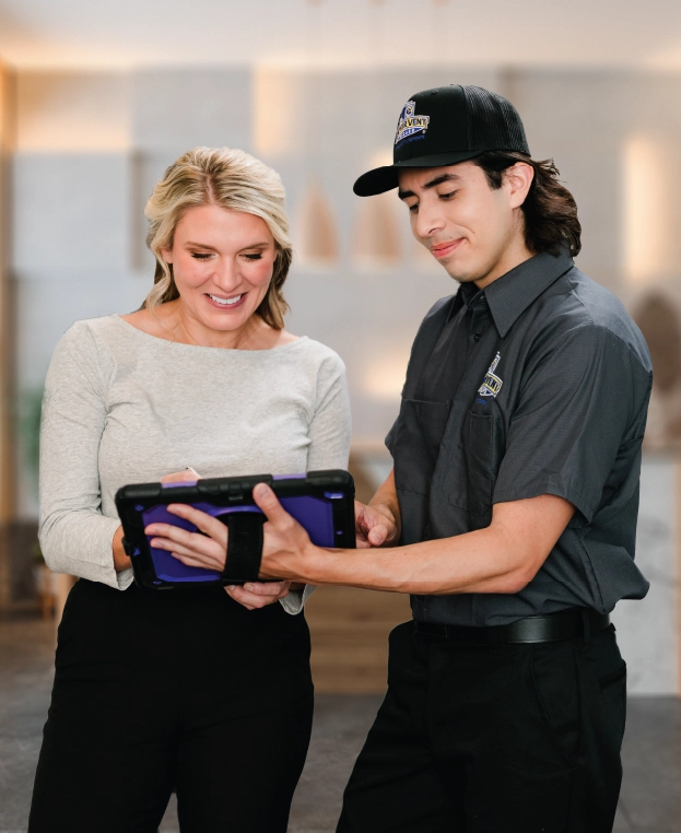 Professional dryer vent cleaning employee showing homeowner company ipad.