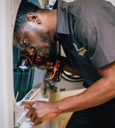 A professional from Dryer Vent Wizard inspects a commercial dryer for issues.