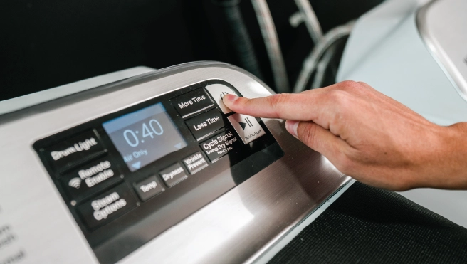 Man pushing power button of a dryer.