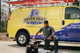 Dryer Vent Wizard professional kneeling outside of company van organizing tools.