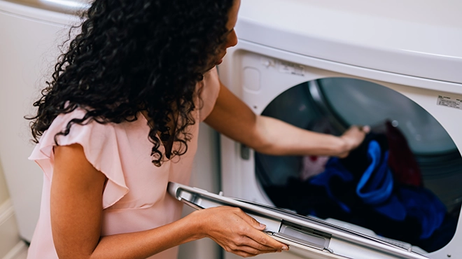 Woman loading dryer with clothes.