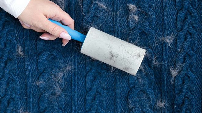 Woman hand using a sticky roller to clean fabrics.