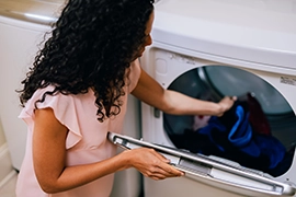 Woman pulling fresh laundry out of dryer.