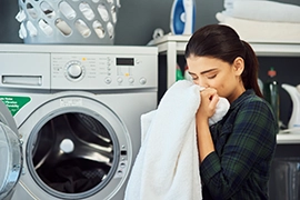 Woman smelling fresh laundry out of dryer.