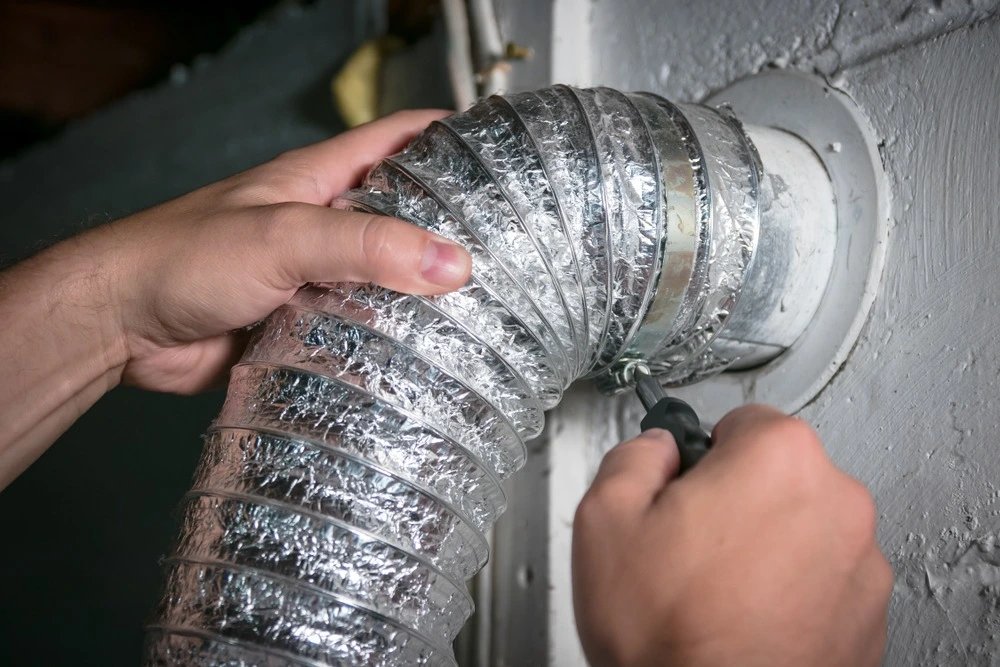 Dryer vent hose being held and screwed into place.