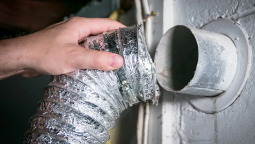 Persons hand holding dryer vent that is not connected.