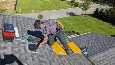 A Dryer Vent Wizard technician on a customer's roof cleaning out their dryer vent.