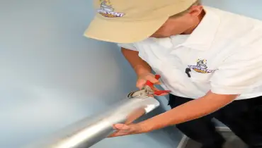 A Dryer Vent Wizard technician cutting a dryer vent.