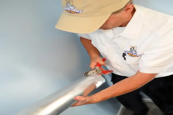 A Dryer Vent Wizard technician cutting a dryer vent.