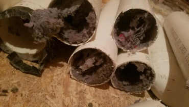 A picture of pvc pipes used as dryer vents clogged with dryer lint.