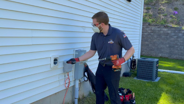 Technician kneeling to clean outdoor dryer vent.