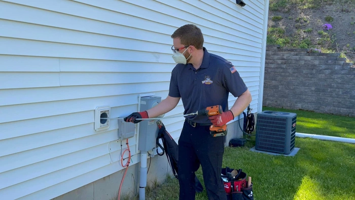 Technician kneeling to clean outdoor dryer vent.