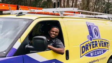 A Dryer Vent Wizard technician driving a Dryer Vent Wizard branded van.