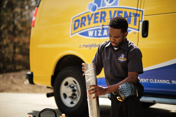 Technician kneeling in front of Dryer Vent Wizard van.